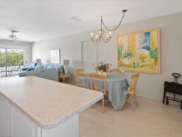Dining room with light tile patterned floors, visible vents, ceiling fan with notable chandelier, and baseboards