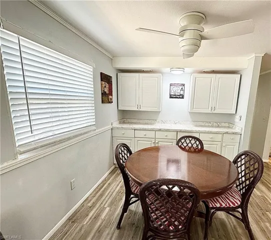 Dining space featuring ceiling fan, light wood-type flooring, and ornamental molding