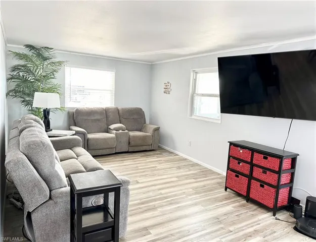 Living room with light hardwood / wood-style floors and ornamental molding