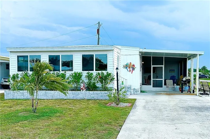 Manufactured / mobile home featuring a front yard and a carport