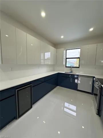 Kitchen with light tile patterned floors, stainless steel electric range oven, sink, and white cabinetry