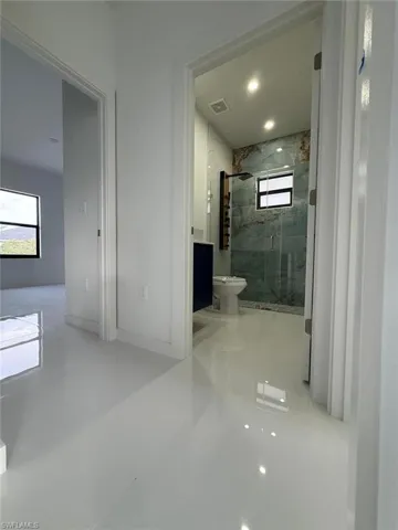 Bathroom featuring toilet, walk in shower, and vanity