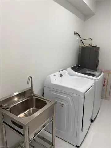 Laundry room with washer and clothes dryer, electric water heater, and sink