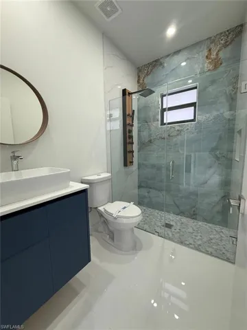 Bathroom featuring toilet, vanity, and a shower with shower door