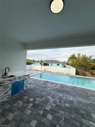View of swimming pool featuring an outdoor kitchen and a wet bar