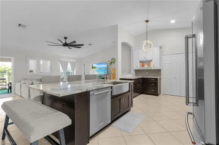 Kitchen featuring vaulted ceiling, stainless steel appliances, visible vents, luxurious granite and white cabinetry