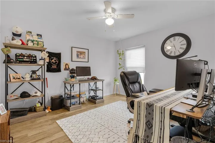 Home office featuring wood finished floors, a ceiling fan, and baseboards