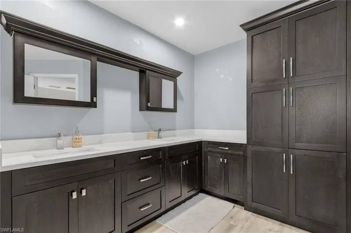 Bathroom with double vanity, wood finished floors, and a sink