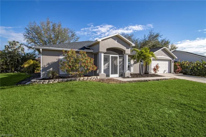 Ranch-style home featuring a front yard, driveway, an attached garage, and stucco siding