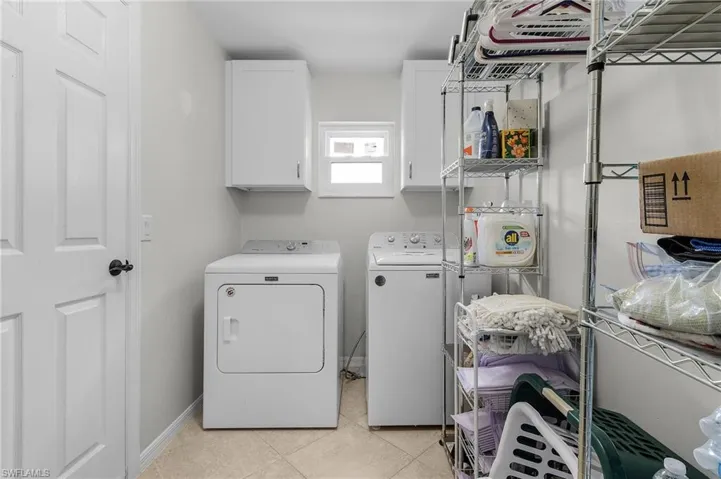 In-House Washroom featuring light tile patterned flooring, cabinet space, baseboards, and separate washer and dryer