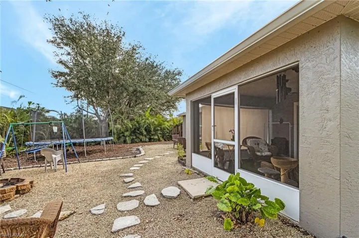 View of yard featuring an outdoor fire pit, a trampoline, and a sunroom