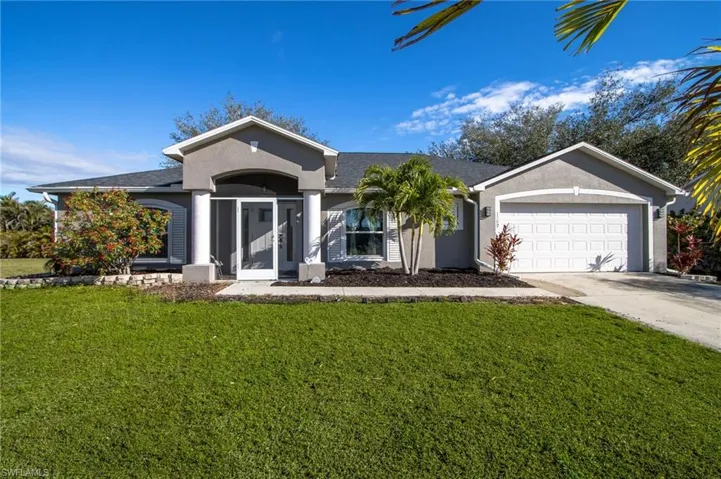 Single story home featuring driveway, a front lawn, an attached garage, and stucco siding