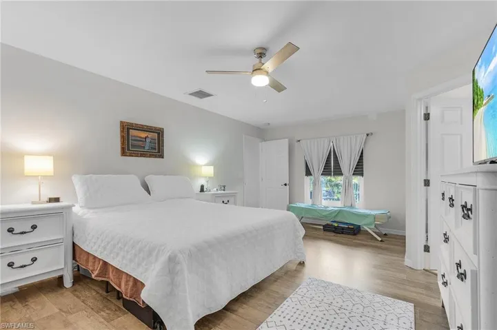 Bedroom featuring light wood finished floors, ceiling fan, visible vents, and baseboards