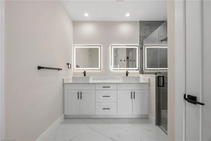 Bathroom featuring double vanity, a shower stall, recessed lighting, and light marble finish flooring
