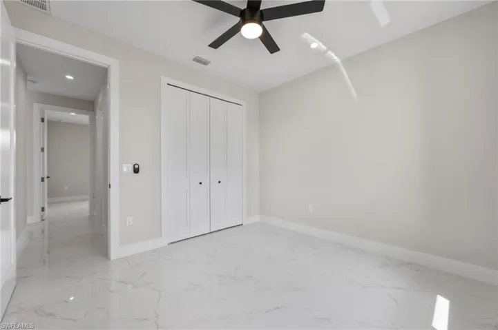 Unfurnished bedroom featuring light marble finish floors, recessed lighting, a closet, and ceiling fan