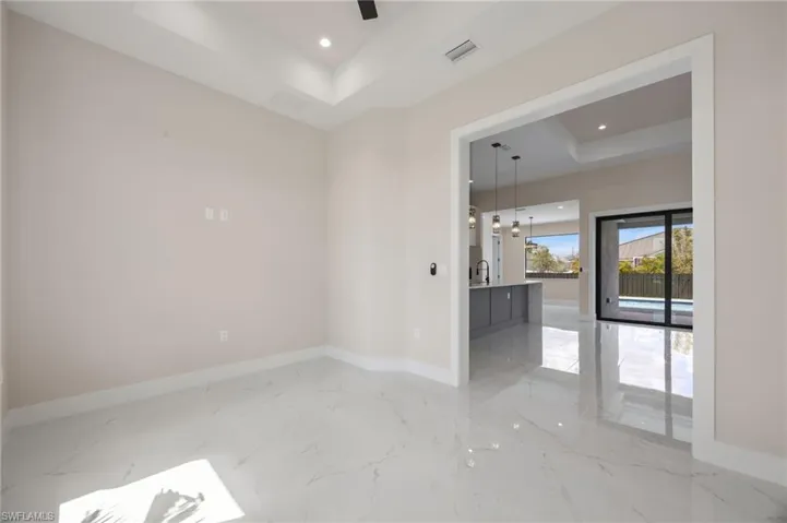 Unfurnished room with a raised ceiling, recessed lighting, and light marble finish floors