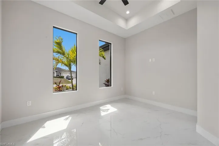 Spare room with a ceiling fan, a raised ceiling, recessed lighting, and light marble finish flooring