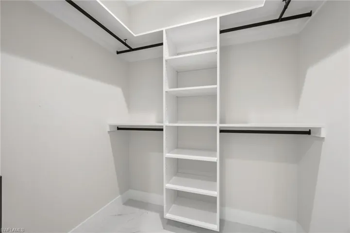 Walk in closet with light marble finish floors