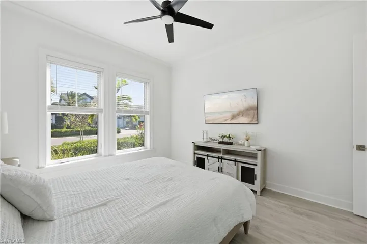 Interior space featuring wood-finish flooring, crown molding, dual-pane windows, and a matte black ceiling fan with integrated lighting
