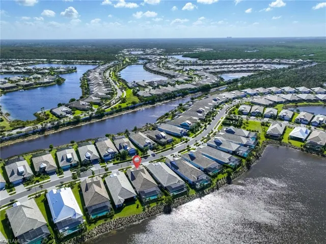 Aerial perspective of a waterfront residential property featuring a tile roof, a screened-in swimming pool enclosure, and direct shoreline access