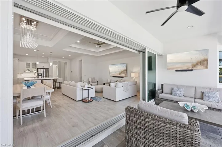 Retractable glass wall system, wood-finish flooring, recessed tray ceilings, contemporary pendant chandelier, and ceiling fans