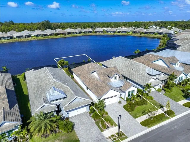 Waterfront property featuring a multi-pitched roofline, paved driveway, and screened-in lanai