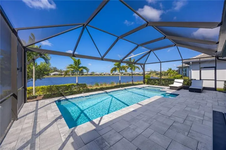 Screened-in pool area featuring paver decking, built-in sun shelf, and water-facing exposure