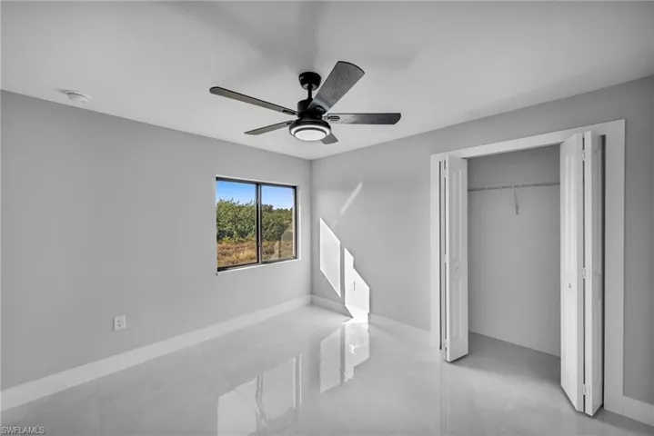 Tiled bedroom with ceiling fan and a closet