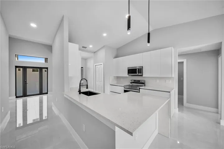 Kitchen featuring decorative light fixtures, white cabinetry, sink, kitchen peninsula, and stainless steel appliances