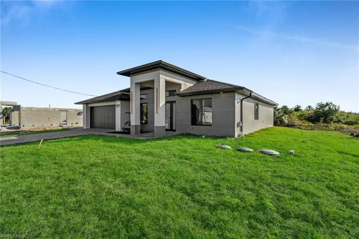 View of front of property with a garage and a front lawn