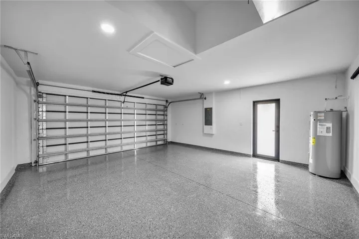 Garage with a garage door opener, electric panel, and water heater