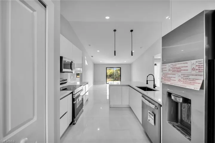 Kitchen with stainless steel appliances, sink, and white cabinets