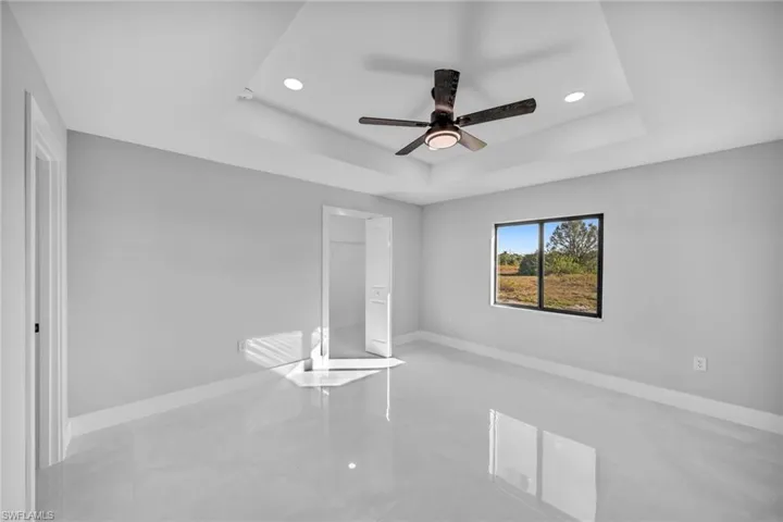 Unfurnished bedroom with a closet, a raised ceiling, and ceiling fan