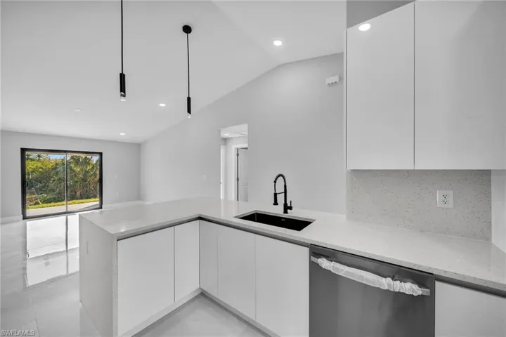 Kitchen featuring white cabinetry, dishwasher, hanging light fixtures, and sink
