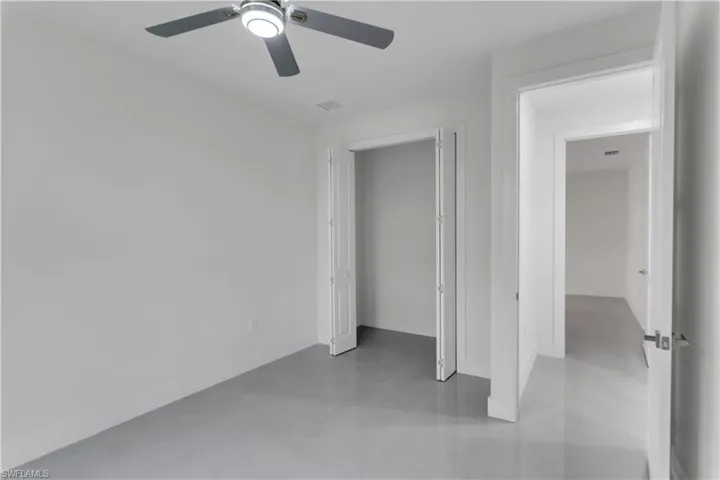 Unfurnished bedroom featuring finished concrete flooring, a closet, visible vents, ceiling fan, and baseboards