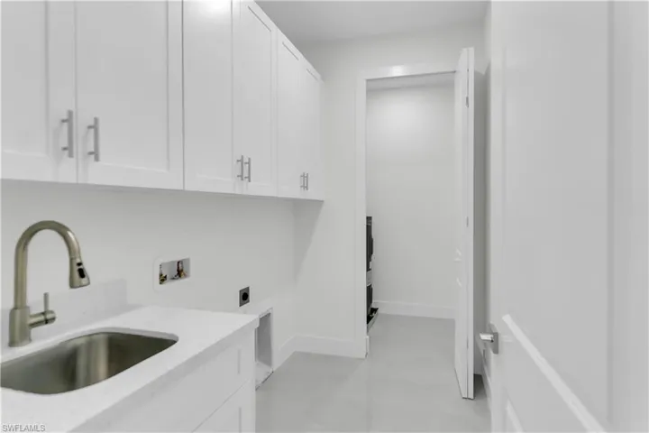 Washroom featuring washer hookup, cabinet space, hookup for an electric dryer, a sink, and baseboards