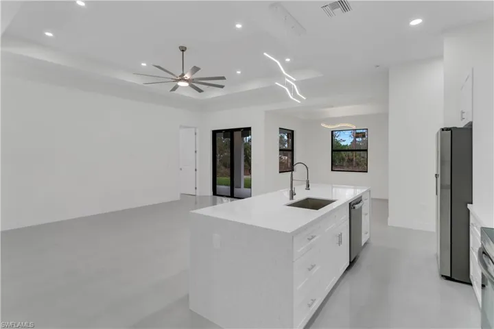 Kitchen with finished concrete flooring, visible vents, a raised ceiling, stainless steel appliances, and a sink