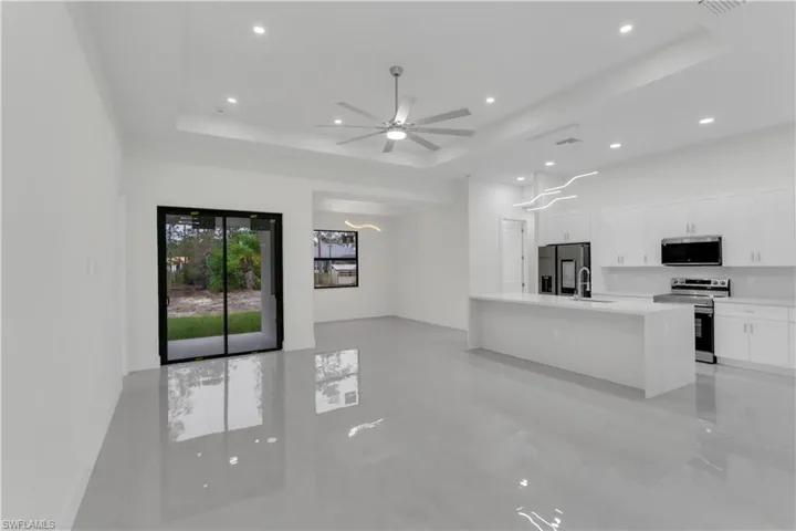 Kitchen featuring a sink, appliances with stainless steel finishes, white cabinets, and a tray ceiling