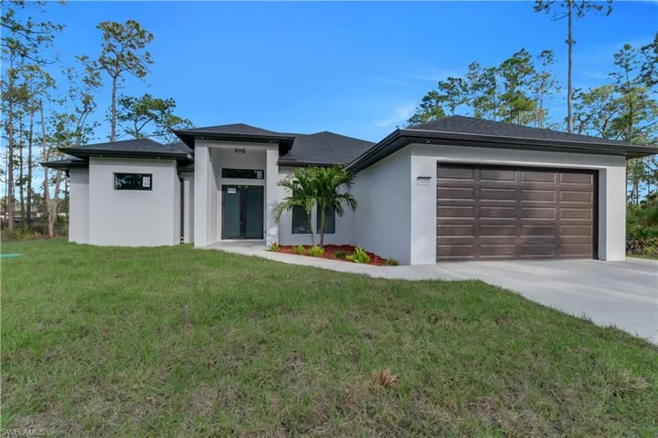 Prairie-style home featuring driveway, a garage, a front yard, and stucco siding