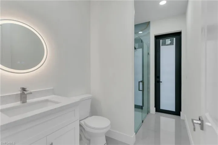 Full bath featuring a stall shower, vanity, toilet, and baseboards