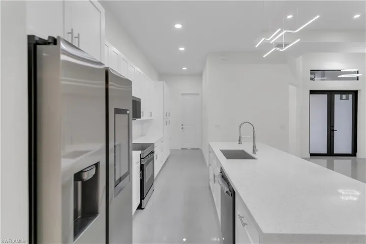 Kitchen with recessed lighting, stainless steel appliances, a sink, white cabinetry, and a center island with sink