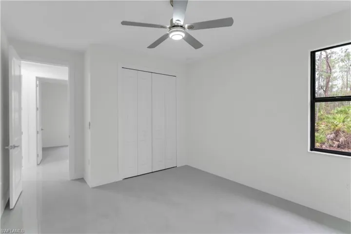 Unfurnished bedroom with ceiling fan, a closet, and concrete flooring