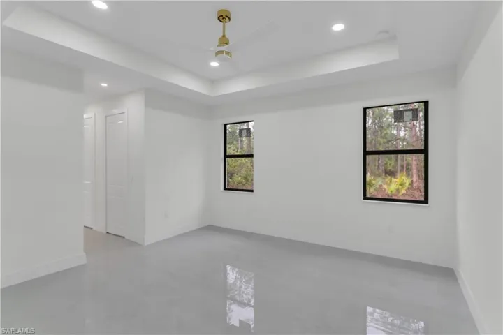 Unfurnished room with a ceiling fan, recessed lighting, baseboards, and a tray ceiling