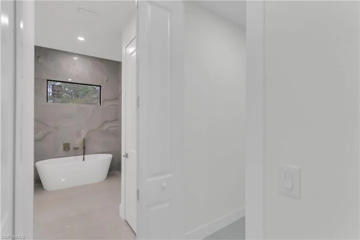 Bathroom with a freestanding tub, tile walls, and recessed lighting