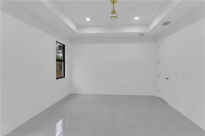 Spare room with recessed lighting, a raised ceiling, visible vents, and baseboards
