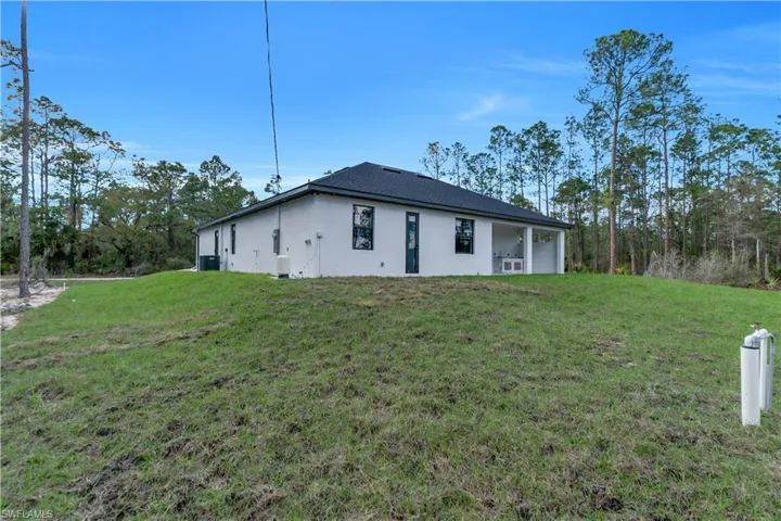 Rear view of house with a lawn and stucco siding