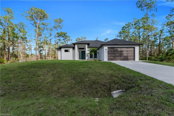 View of front of property featuring a front yard, concrete driveway, and an attached garage
