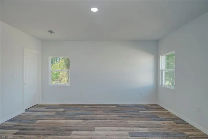 Unfurnished room featuring wood finished floors, plenty of natural light, and recessed lighting