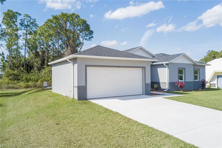 Ranch-style house featuring a front lawn, stucco siding, driveway, an attached garage, and roof with shingles