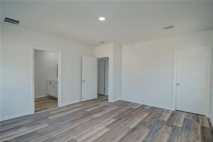 Unfurnished bedroom with light wood-style floors, ensuite bath, and recessed lighting